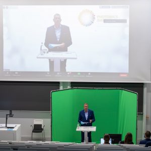 Prof. Andreas Tünnermann in front of a green screen in the lecture hall.